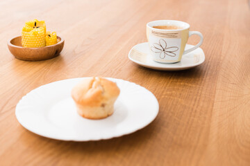 Fresh muffin with coffee for breakfast. Candel on the desk.