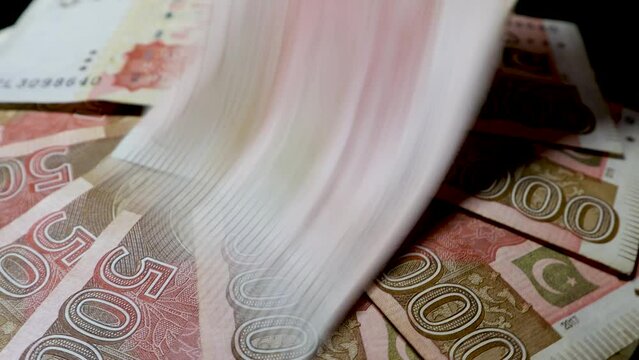 A man placing and counting Pak Rupee banknotes of 5000 denominations, rotating on an automatic display table, concept footage for inflation, financial crisis, rich, and tax. 