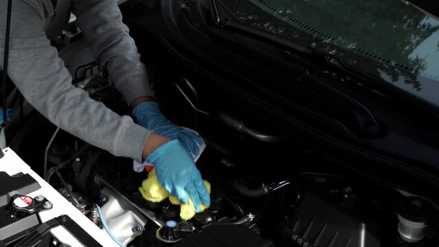 Close up of a women hand washing and wiping the car with cloth. Vehicle wash and cleaning the car engine compartment or car detailing services concept.