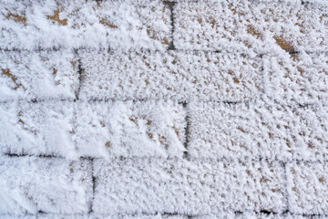 Close-up of a brick wall covered with large flakes of frost. Background
