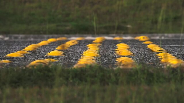 Time lapse close up of yellow semi sphere road studs or speed bump at night on asphalt road. Many cars passing fast by traffic speed control system