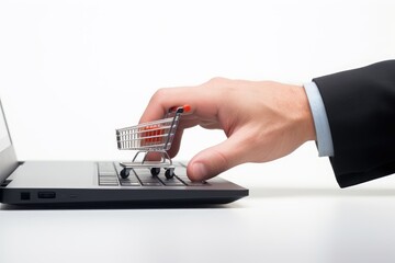 Hand pushing a miniature shopping cart on a laptop keyboard.