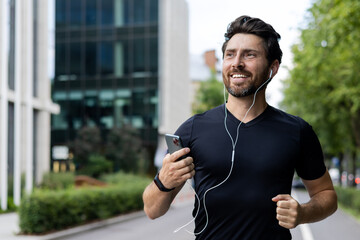 Joyful adult male jogging in urban setting with earphones and smartphone, fitness and technology concept