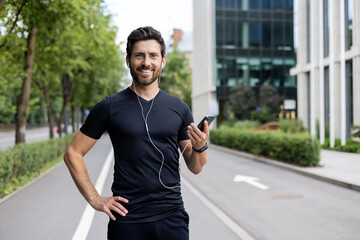 Smiling athletic man with earphones using smartphone during urban workout, fitness and healthy lifestyle concept