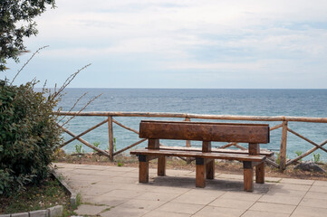 Wooden bench in a green area facing the seashore.