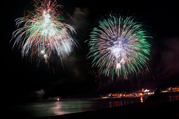Firework display over the shoreline at night for the celebration.