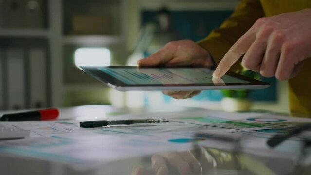 Monitoring. A top manager in worker's clothes studies digital production indicators in a creative office. Company employees perform audits and analytics, introduce new organizational methods, progress