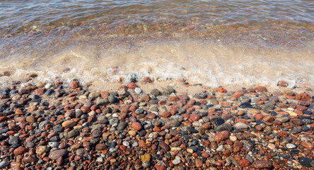 Pebbles on the shore of the Baltic Sea are washed by clear sea water