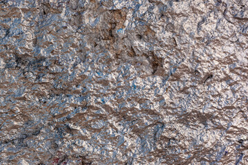 The nice, vintage rough and wrinkled concrete wall is painted with silver and rose gold shining paint