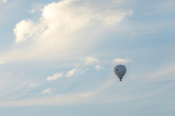 Hot air balloon silhouette in the distance of blue sky with white clouds. Photo from below