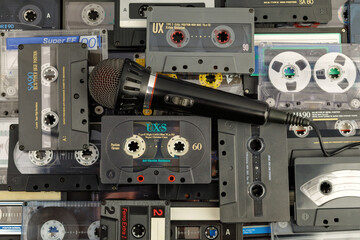 70-90s nostalgia karaoke microphone on audio cassettes background, top view