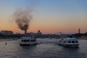 Cruise tour on the Moskva river, fire with black smoke in the city centre of Moscow in Russia. High quality photo.