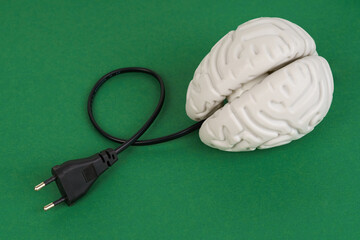 Brain with an electric wire for charging on a green background.