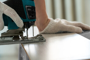 Man sawing laminate. Man is repairing the floor in the house, laminate flooring in the style of old boards