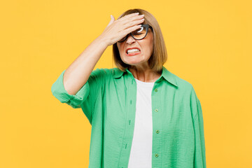 Elderly sad blonde woman 50s years old wear green shirt glasses casual clothes put hand on face...