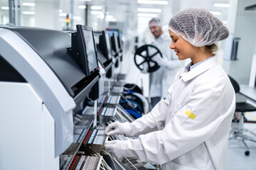 Factory workers operating advanced semiconductor production machine in electronics industry. - obrazy, fototapety, plakaty