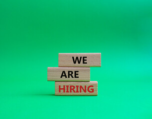We are Hiring symbol. Concept words We are Hiring on wooden blocks. Beautiful green background. Business and We are Hiring concept. Copy space.