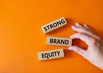 Strong Brand Equity symbol. Concept words Strong Brand Equity on wooden blocks. Businessman hand. Beautiful orange background. Business and Strong Brand Equity concept. Copy space