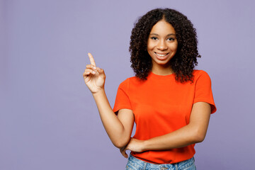 Little happy kid teen girl of African American ethnicity she wear orange t-shirt point index finger...