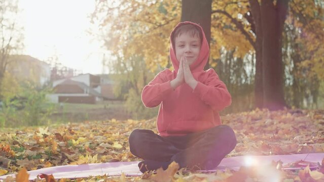 Child boy meditating at sunset in the park. Yoga classes for teenagers looking for balance and a calm active lifestyle. High quality 4k footage