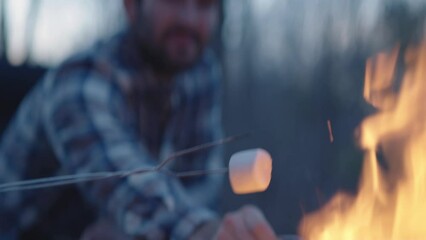 Young man and woman sit beside a fire and make s’mores  - Powered by Adobe