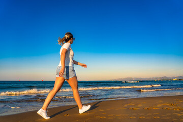 Beach holiday - beautiful woman walking, running on sunny beach - Costa Dorada Spain 