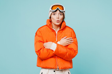 Freezing skier young woman wearing warm padded windbreaker jacket hat ski goggles mask hug herself...