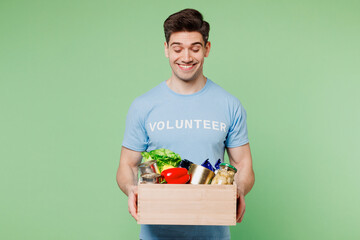 Young happy man wears blue t-shirt white title volunteer give box with vegetarian vegan food...
