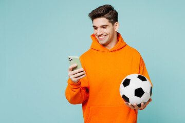 Young happy man fan wears orange hoody casual clothes use mobile cell phone cheer up support...