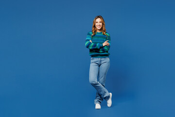 Full body smiling happy fun young woman she wears knitted sweater casual clothes hold hands crossed folded look camera isolated on plain blue cyan color background studio portrait. Lifestyle concept.