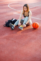 Woman tying shoelace on basketball court getting ready for workout