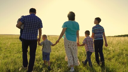Family travel parents children summer. Big happy family on walk in park. Mom, children, dad are walking along green grass in meadow. Kid child, son, boy, family team, holding hands, walk together