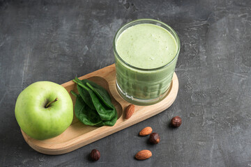 Green detox smoothie in a glass, blended vegetarian drink from spinach leaves, apple, banana fruit...