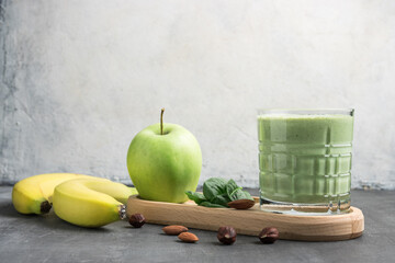 Green detox smoothie in a glass, blended vegetarian drink from spinach leaves, apple, banana fruit...