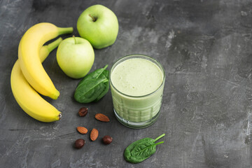 Green detox smoothie in a glass, blended vegetarian drink from spinach leaves, apple, banana fruit...