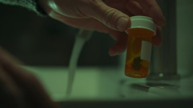 In the bathroom of his home, a man takes pills from an orange bottle, following the recommendations of his doctor. Modern treatment methods help him maintain his health at an acceptable level
