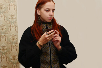 Selfie portraits of a red-haired woman in a jacket in ethnic Ukrainian style, green embroidered shirt on a white background.