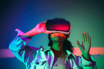 Young african american woman using VR headset, interacting with cyberspace, exploring virtual world