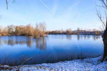 View over the Swan Lake with swans and water birds near Mering on a cold winter's day with a blue...
