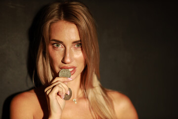 Beautiful blonde woman biting old silver coin