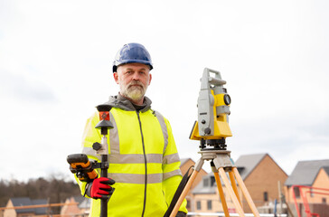 Surveyor builder site engineer with theodolite total station at construction site outdoors during...