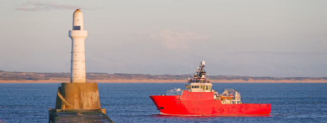 Ship arriving at Aberdeen harbour after passing Girdle Ness Lighthouse - obrazy, fototapety, plakaty
