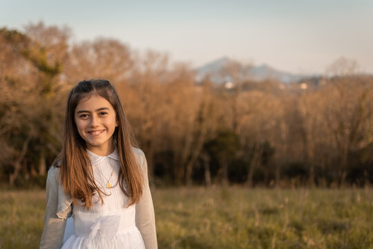 Sweet and smiling girl celebrating her communion with her first communion dress while enjoying nature and the countryside, image with right copyspace