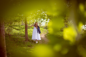 Beautiful girl in first communion dress celebrating her day in a beautiful park during a sunny...