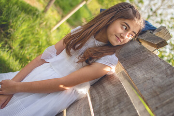 Beautiful girl in first communion dress celebrating her day in a beautiful park during a sunny...