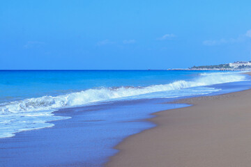 Sandy beach sea shore with blue wave and white foam. Sea ​​waves on the sand on the beach. Blue sea waves on the beach for background. Beach sand and soft wave background. Vacation travel holiday 