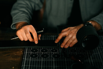 Leatherworker tanner draws, measures with ruler. Tanner works with leather, small business,...