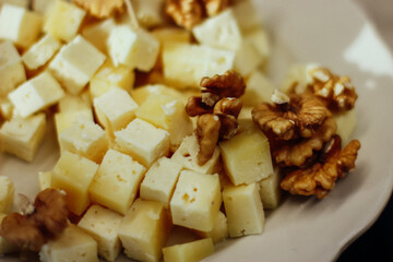 a plate of cheese and walnut. Two types of cheese on a board. Closeup