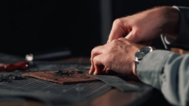 close-up of tanner'hands with bevel cutter chamfers edge of leather Working process of natural leather processing.