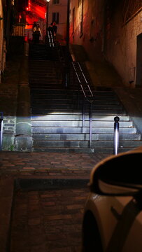 Larges escaliers en pierre historique éclairés par des phares de voiture, ambiance nocturne, soirée, lampadaires allumés, beauté urbaine et gothique à Paris, instant photographique, montée des marches